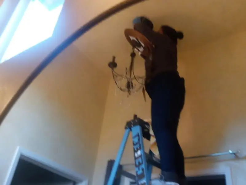 Electrician installing a chandelier in a Zelienople residence